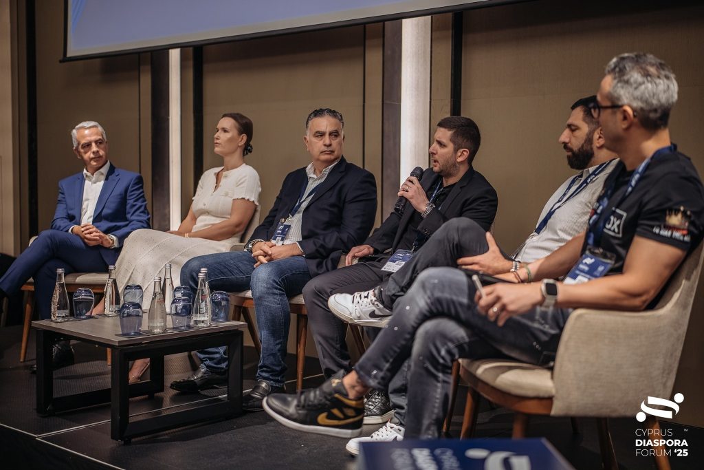 Andreas Vassilopoulos speaking during a panel discussion at the Cyprus Diaspora Forum 2025, seated among fellow panelists on stage.