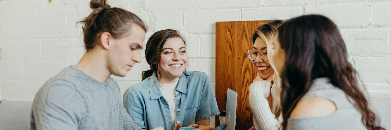 Group of young professionals collaborating and smiling while working together on a laptop